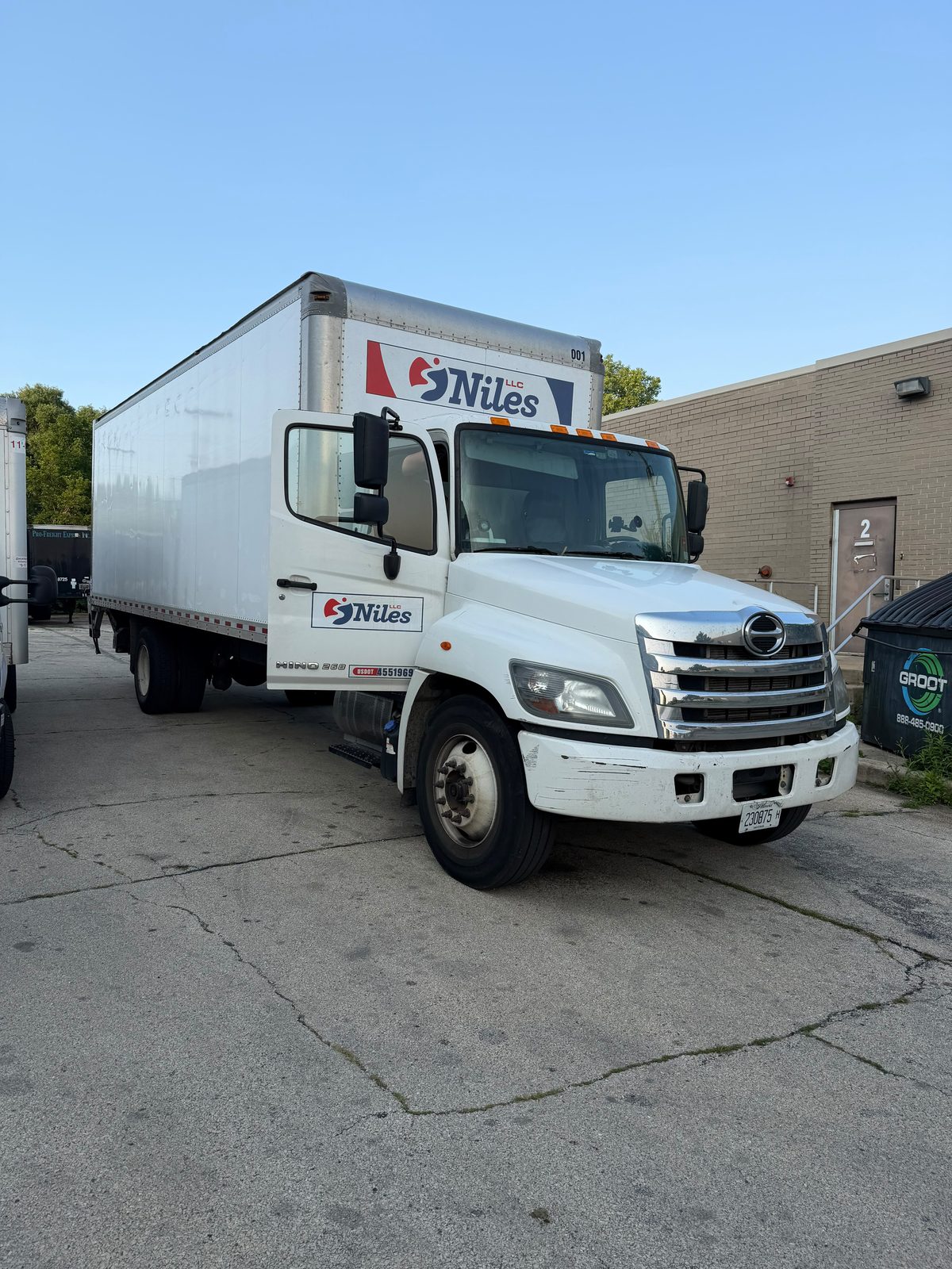 Niles LLC crew standing with the company cargo van and 26-foot box truck